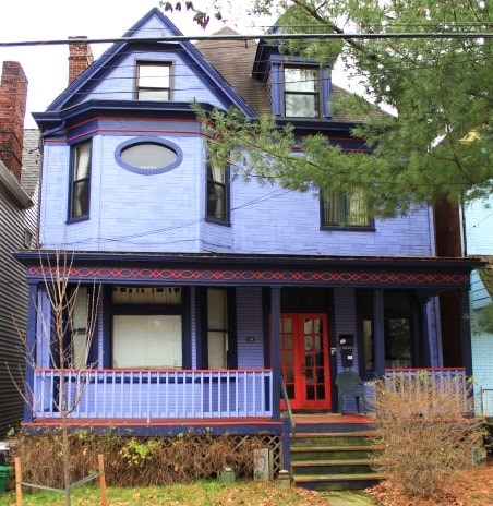 A blue house with a red door and a porch.