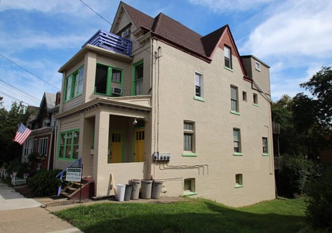 a white house with green windows and a roof