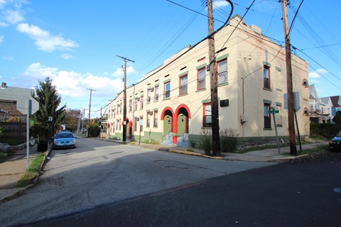 A street view of a building with a blue car parked in front.