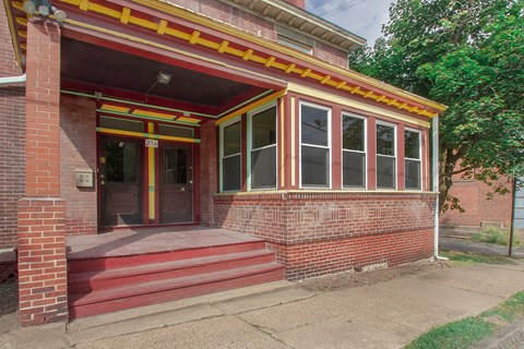 A red brick house with a yellow stripe and a red door.