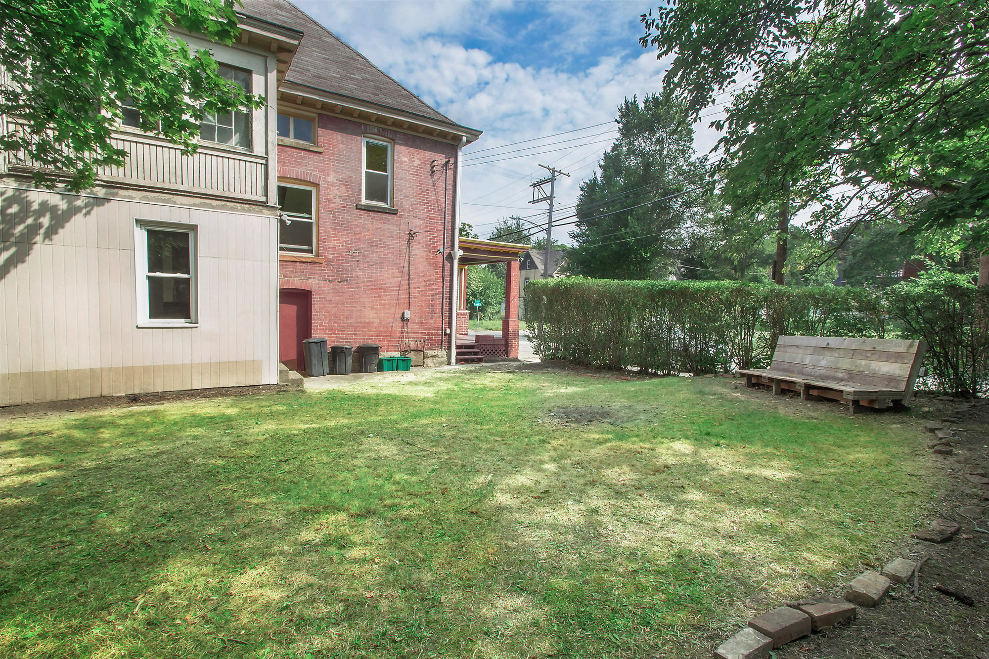 A backyard with a wooden bench and a red door.