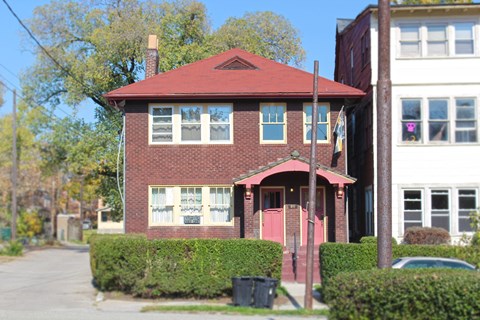 a brick house with a red roof on a street
