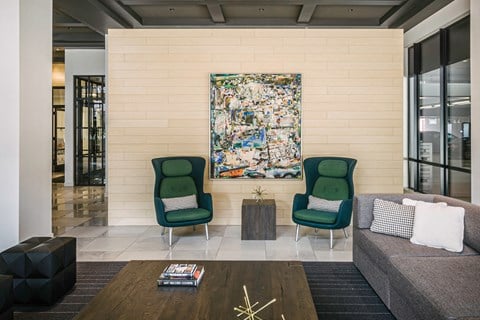 a living room with green chairs and a painting on the wall