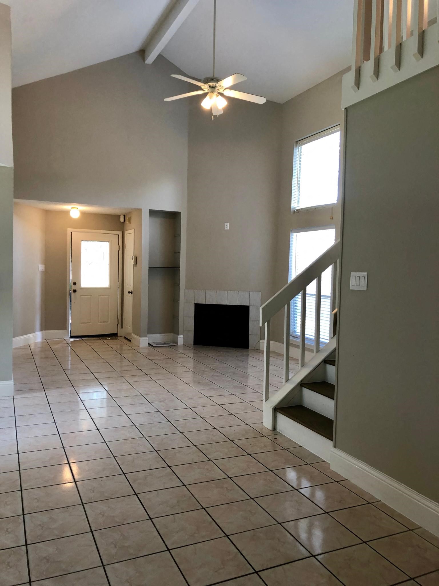 an empty living room with a tile floor and a ceiling fan