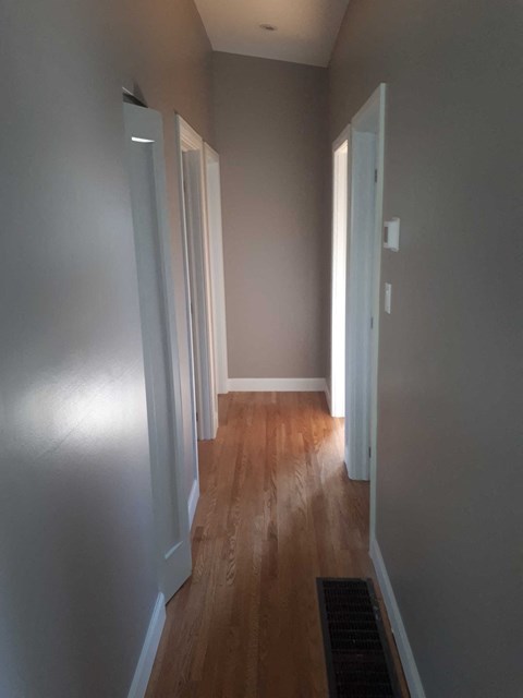 a hallway with wood floors and grey walls and white doors