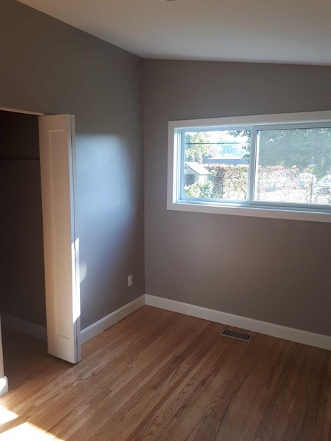 an empty room with a window and wooden floors