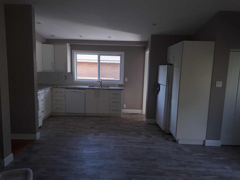 an empty kitchen with white cabinets and a window