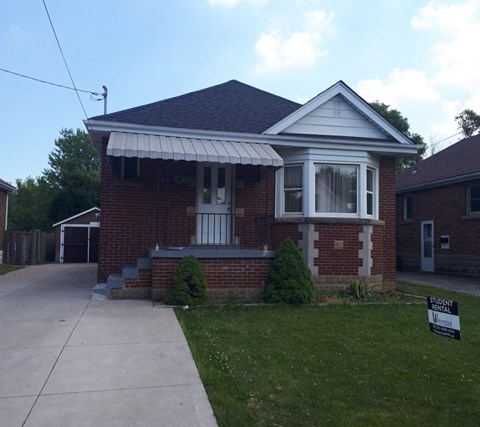 a small brick house with a sidewalk in front of it