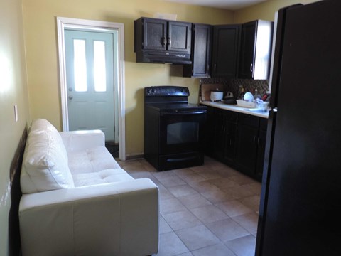 a kitchen with black cabinets and a white couch