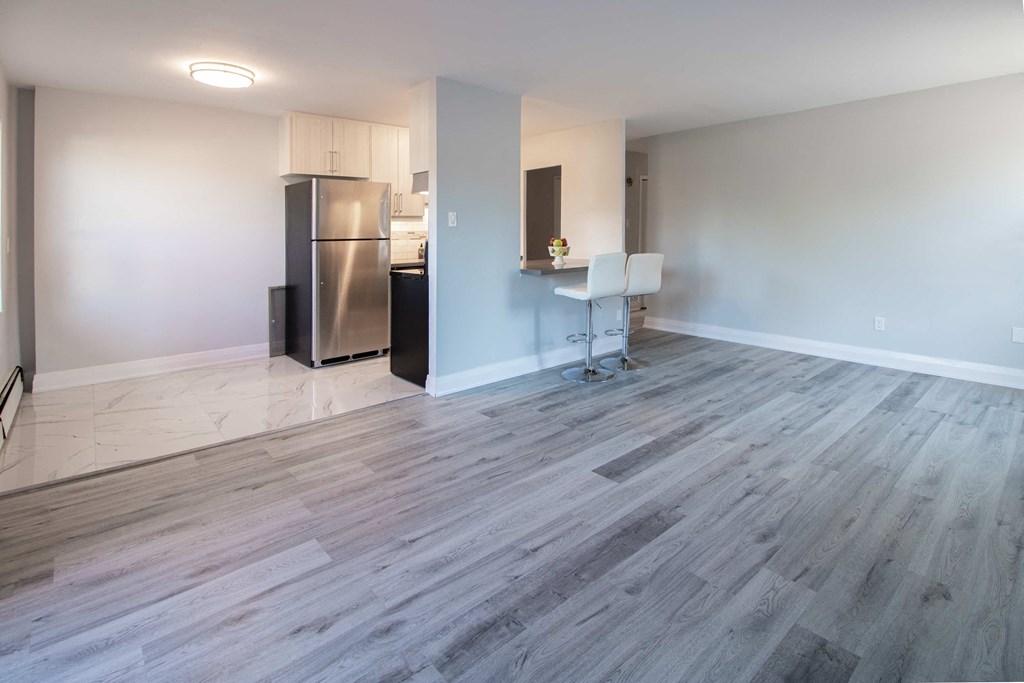 a renovated living room with wood flooring and a stainless steel refrigerator