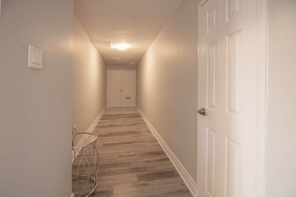 a long hallway with white walls and a white door