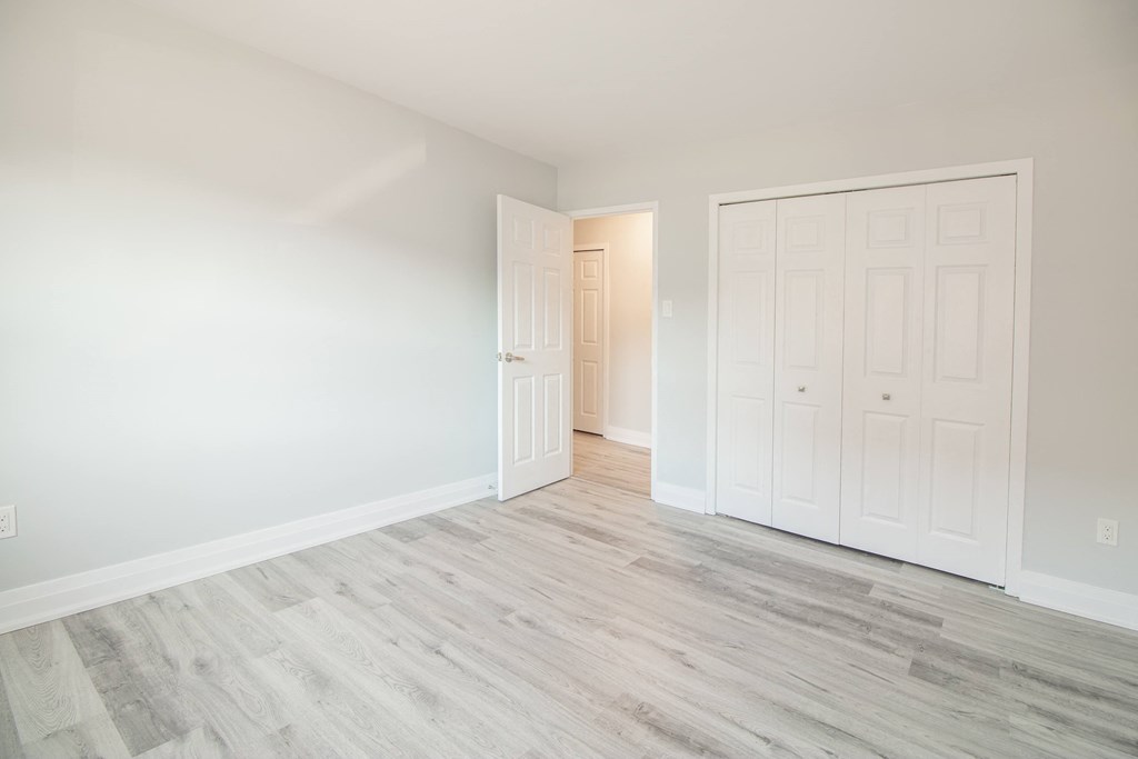 a bedroom with white walls and a door to a closet