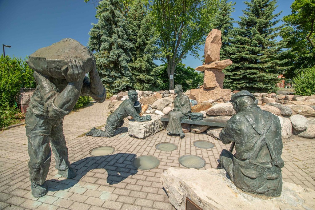 a group of statues of people sitting and standing around a statue