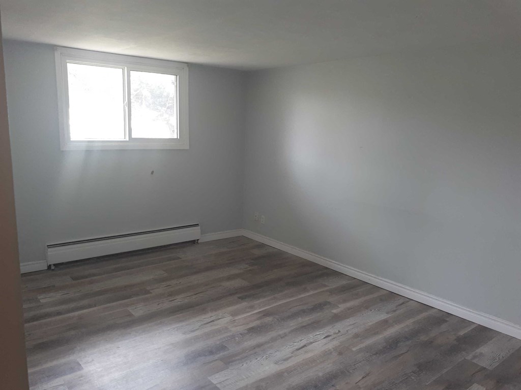 a room with white walls and a window and wooden floors