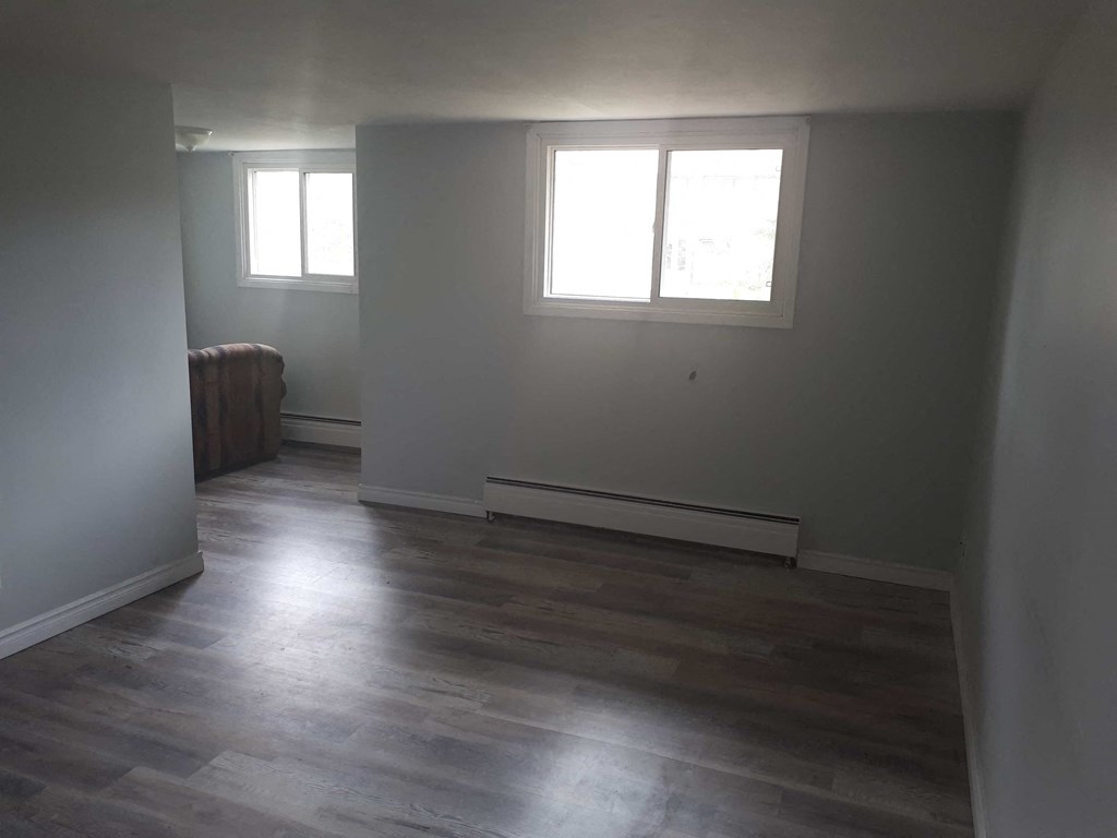 an empty living room with white walls and wood floors