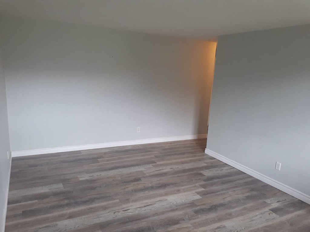 a empty room with wood flooring and white walls