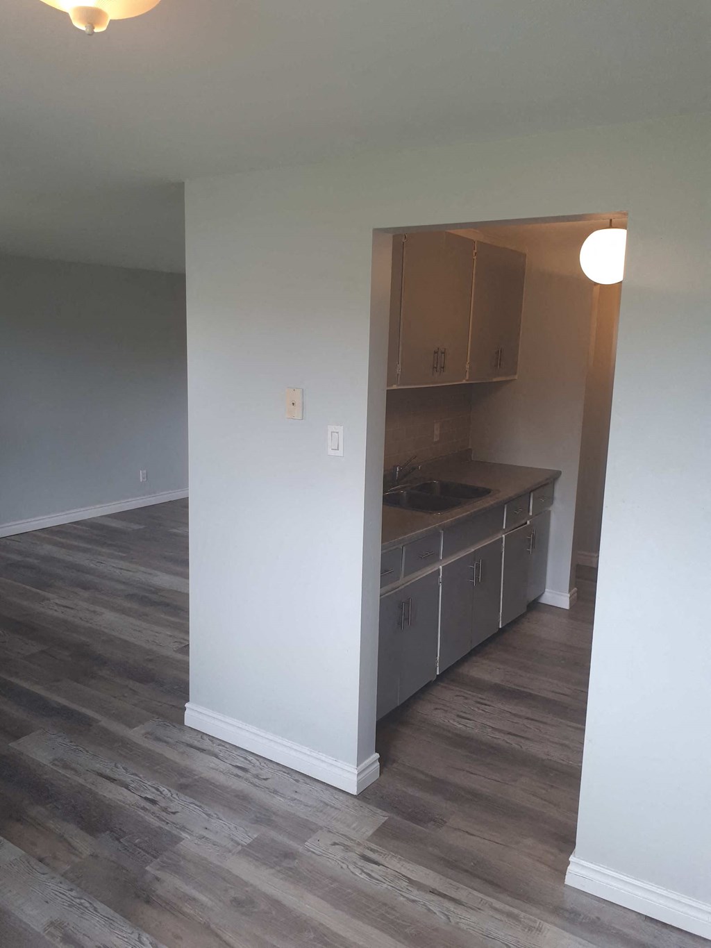 an empty kitchen in an empty house with a wooden floor