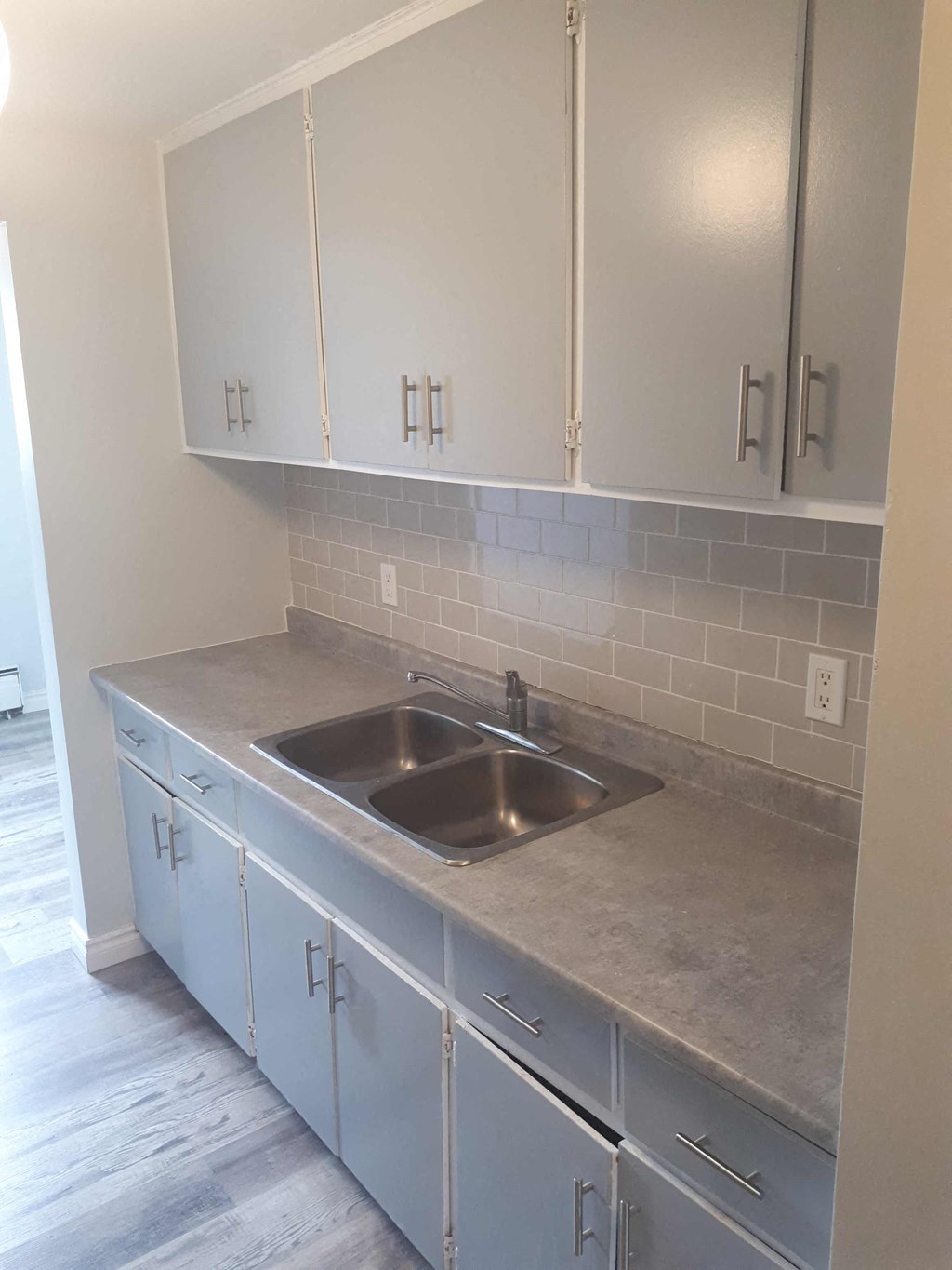 an empty kitchen with white cabinets and a sink