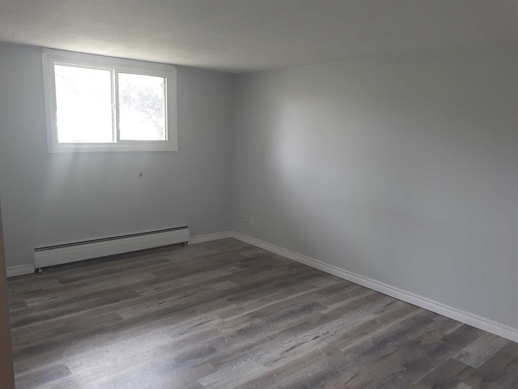 a room with white walls and a window and wooden floors