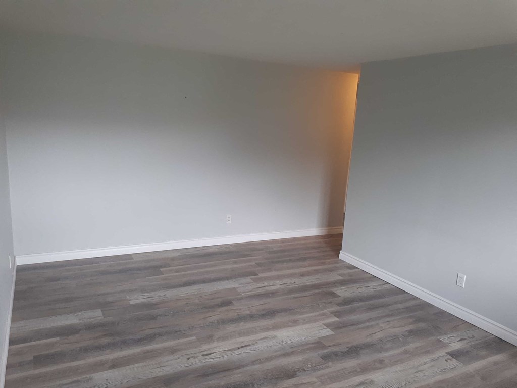 a empty room with wood flooring and white walls