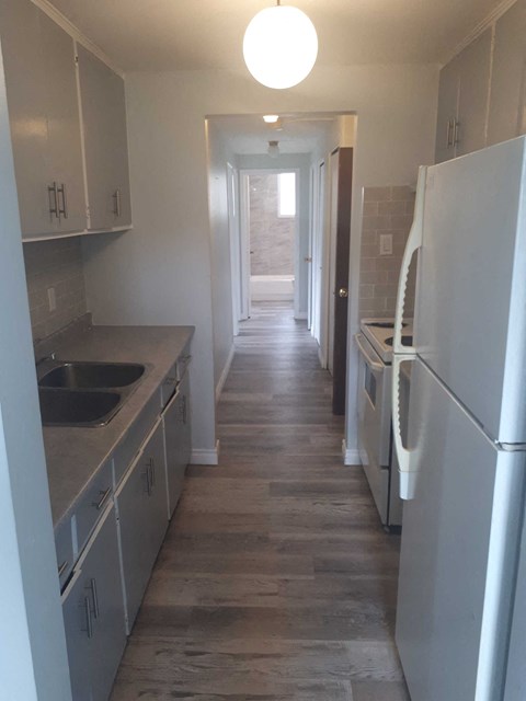 a kitchen with white cabinets and stainless steel appliances and a hallway