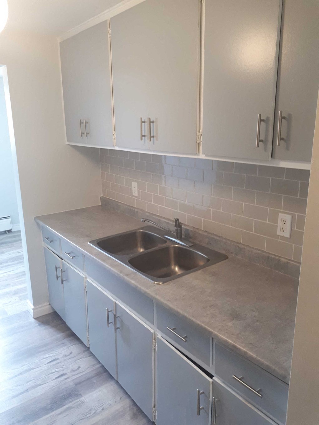 an empty kitchen with white cabinets and a sink