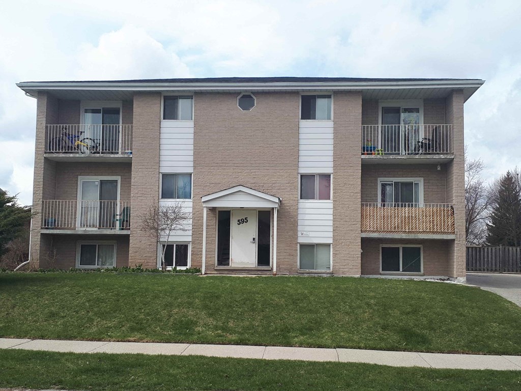 the front of a brick apartment building with a lawn