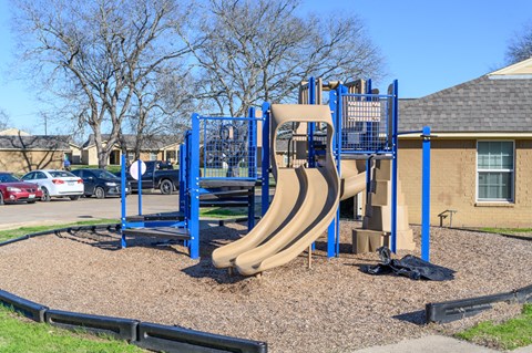 A playground with a blue and tan slide.