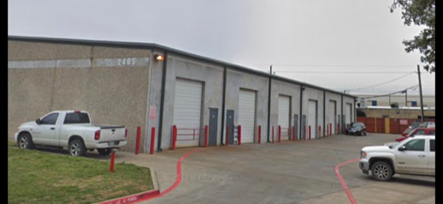 A white truck is parked in front of a building with the number 2405 on it.