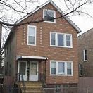 A brown brick house with a white door and windows.