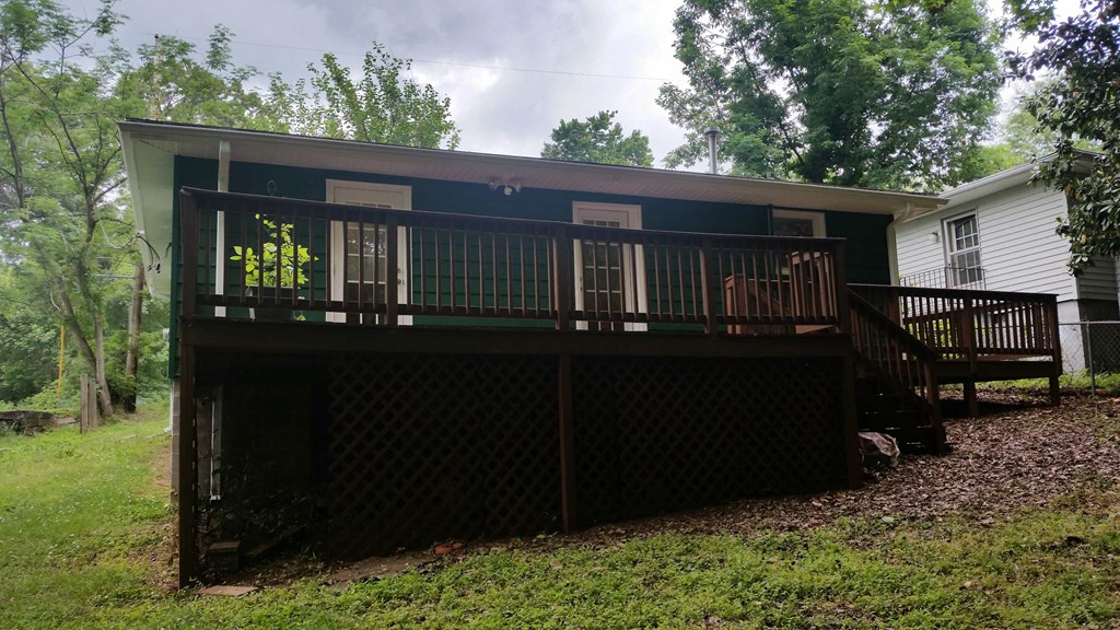 A wooden deck with a lattice fence and a white house in the background.