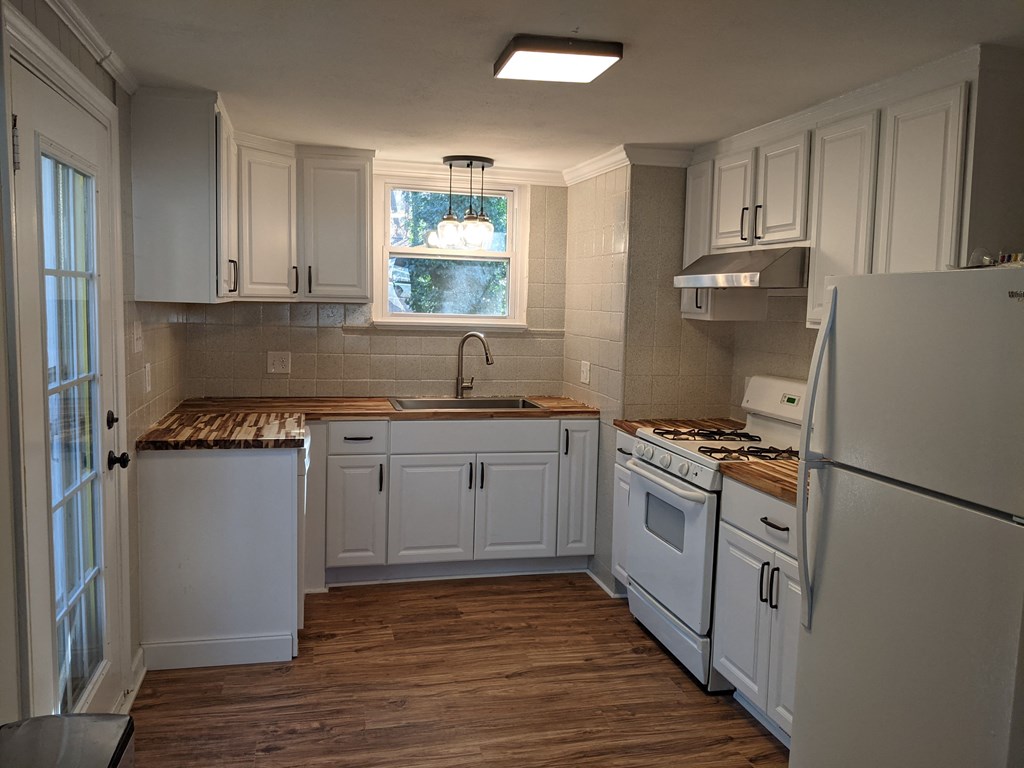 A kitchen with white cabinets and a wooden countertop.