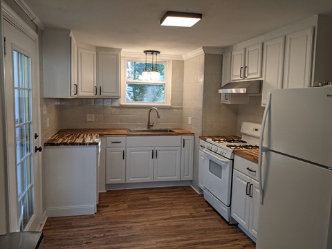 A kitchen with white cabinets and a wooden countertop.