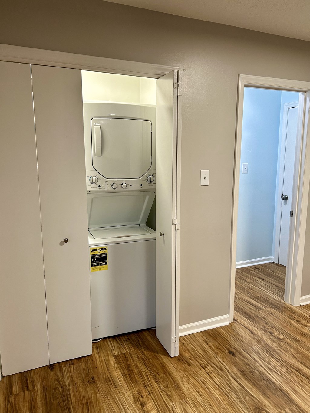 A small white fridge is in a room with a wooden floor.