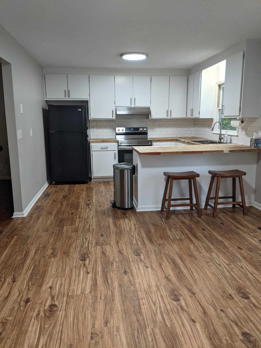 A kitchen with wooden floors and white cabinets.