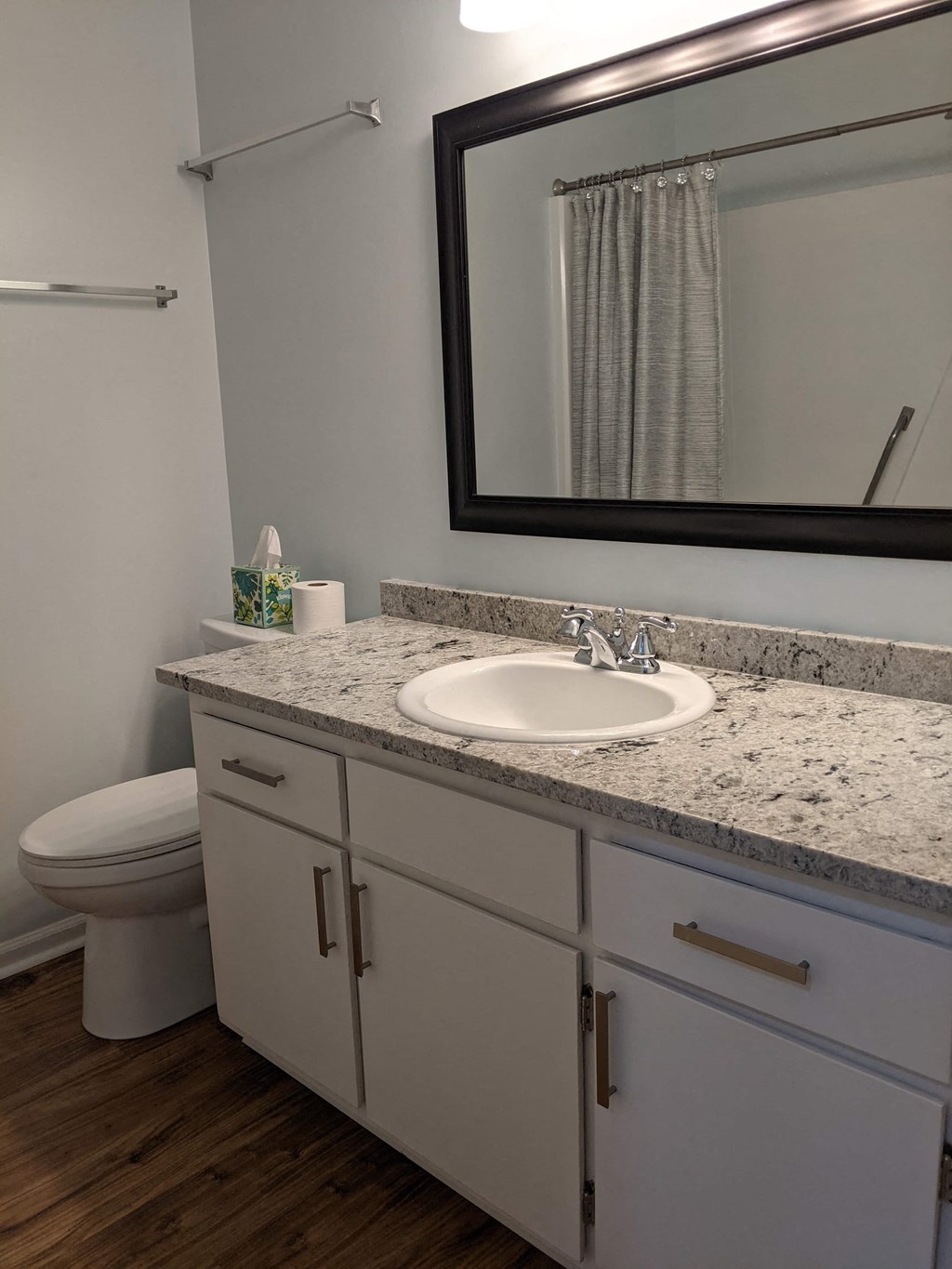 A bathroom with a sink, toilet, and a mirror.