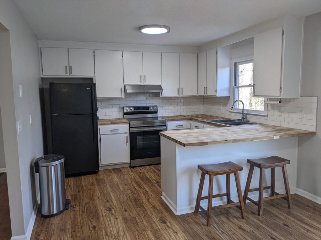 A kitchen with black appliances and wooden floors.