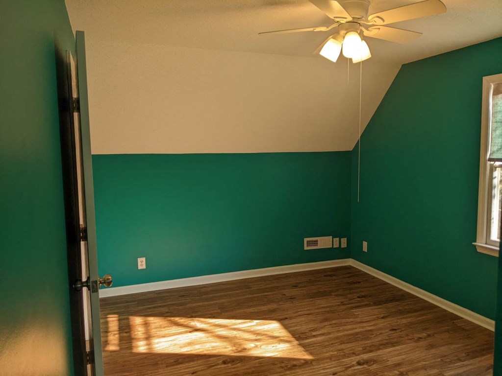 A room with a ceiling fan and a door.