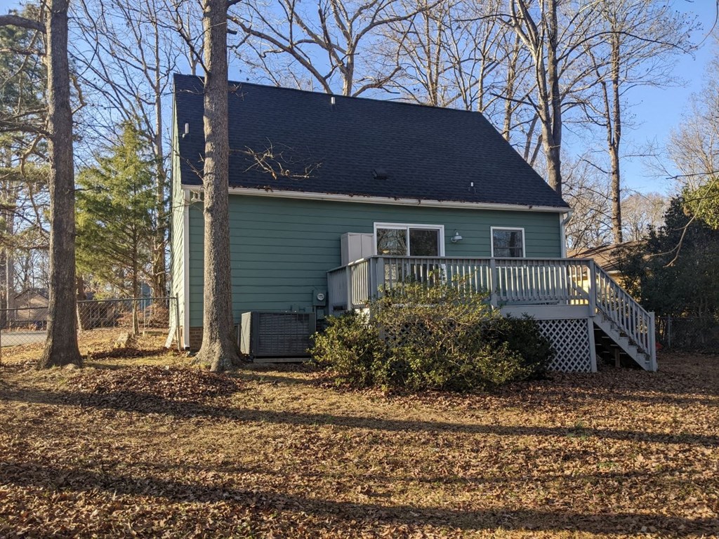 A house with a green siding and a black roof with a white porch.