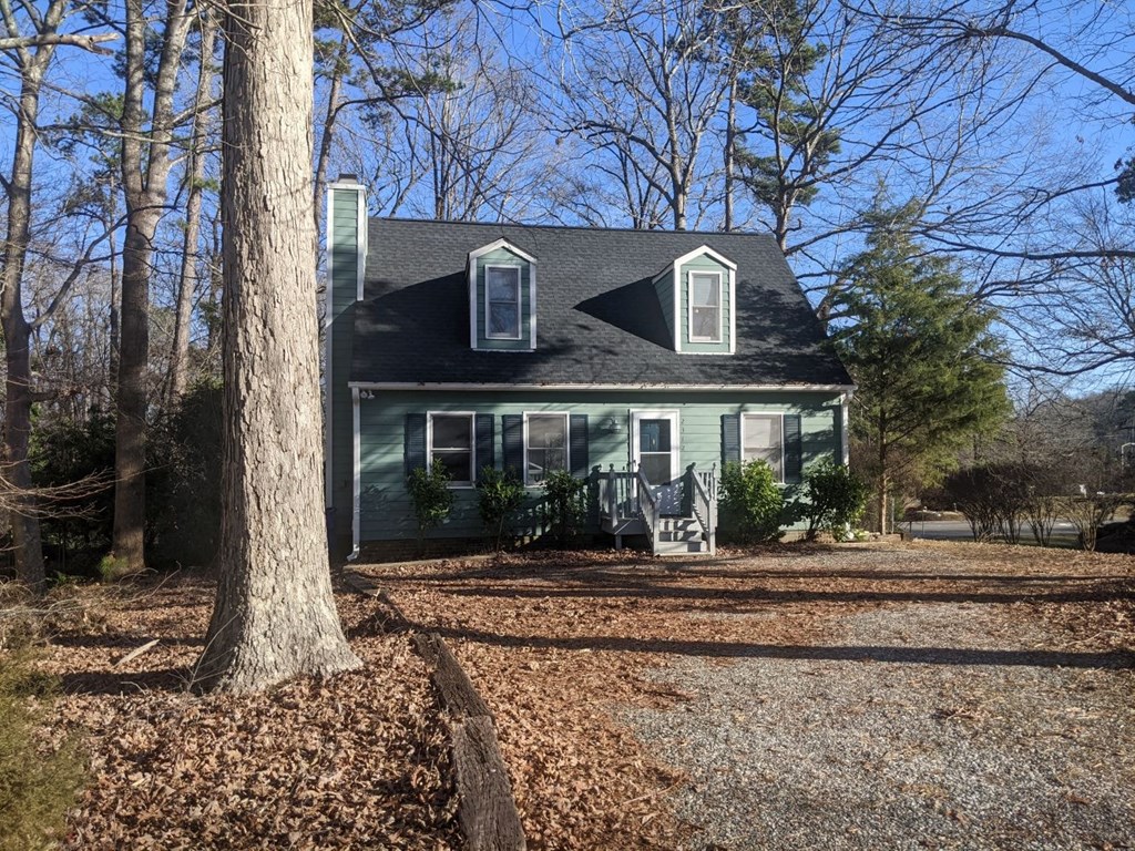 A house with a grey roof and white trim is surrounded by trees.