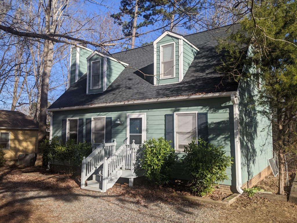 A house with a green exterior and a grey roof.