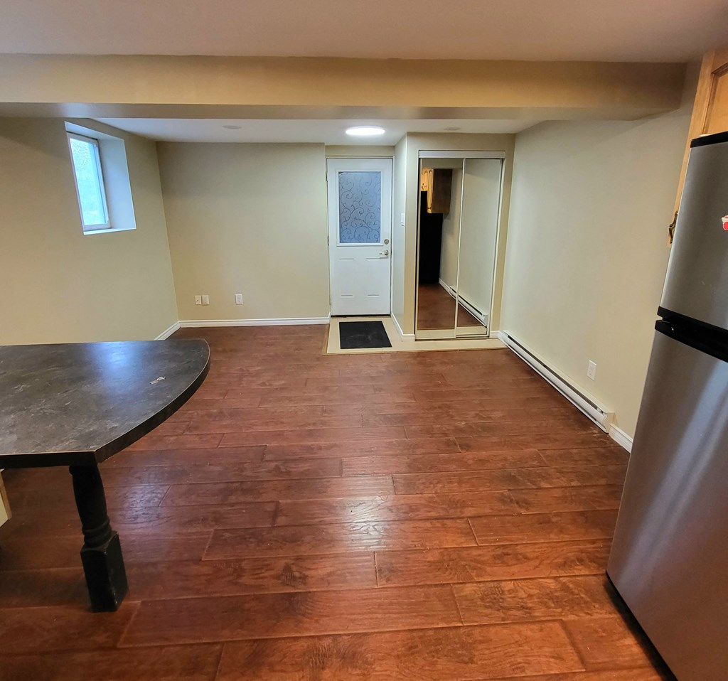 a kitchen and living room with wood floors and a door to a hallway