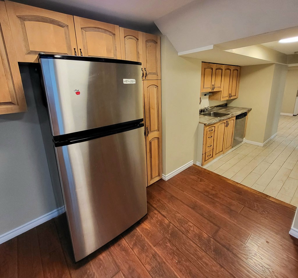 a kitchen with a stainless steel refrigerator and wooden floors