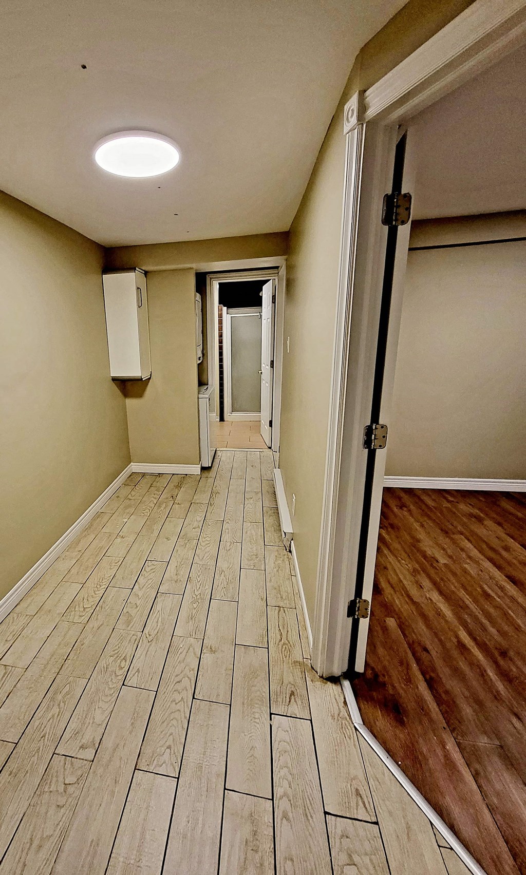 a hallway with wood flooring and a door to a room