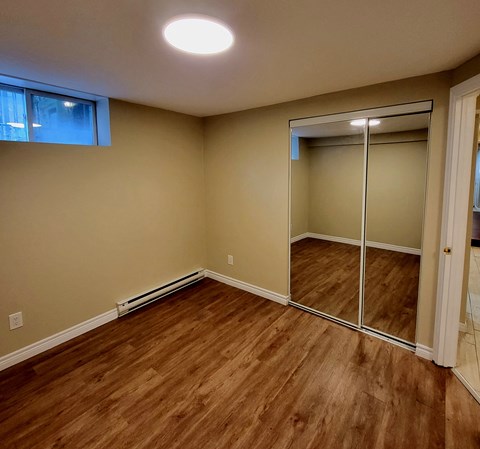 a bedroom with a mirrored closet and a hard wood floor