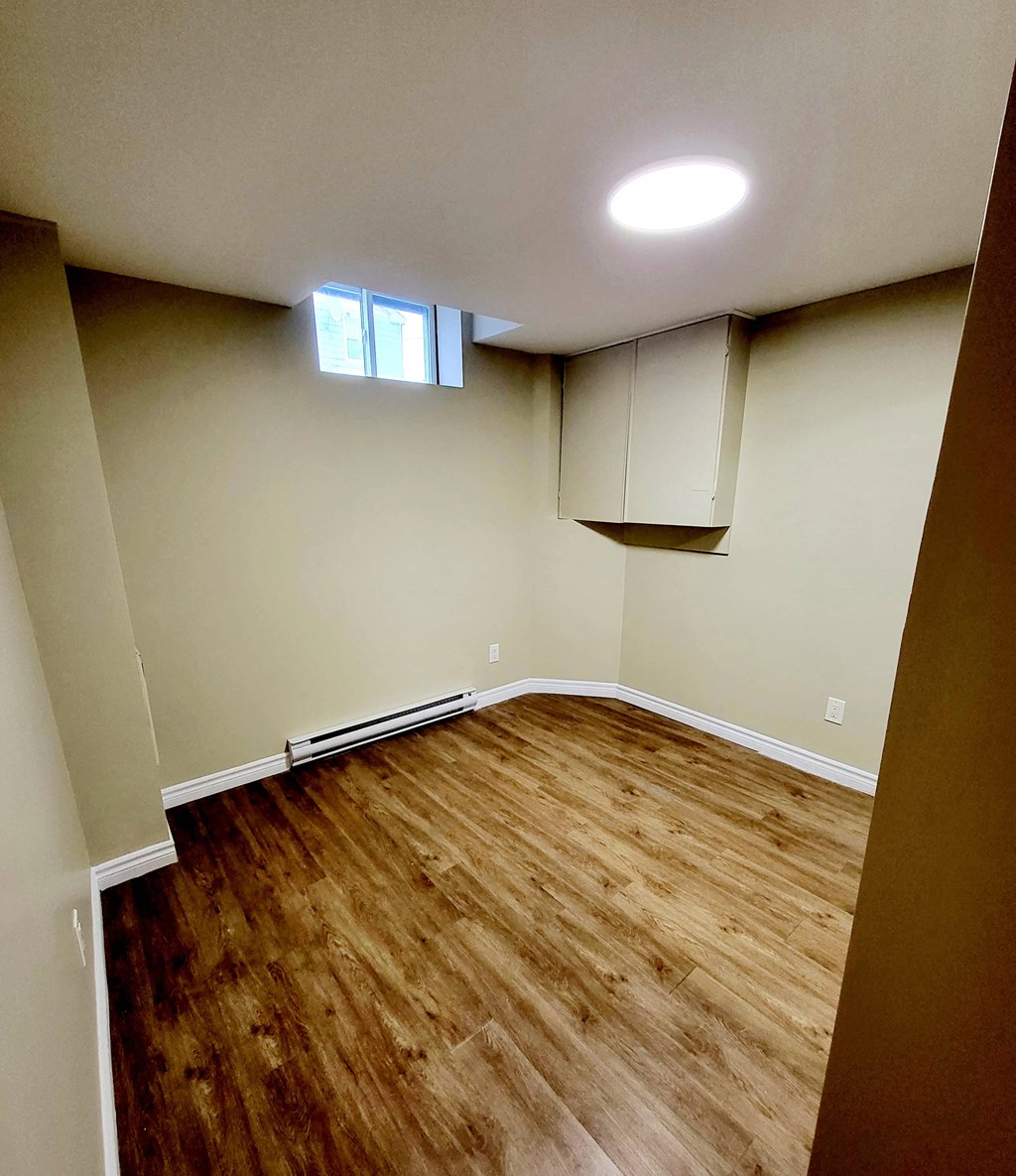 an empty living room with wood flooring and a window