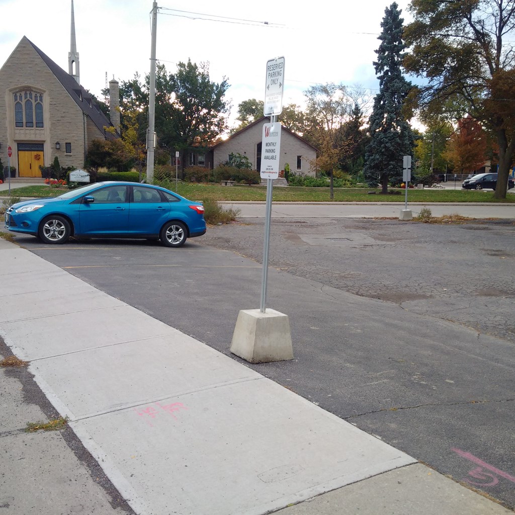 a blue car parked next to a street sign