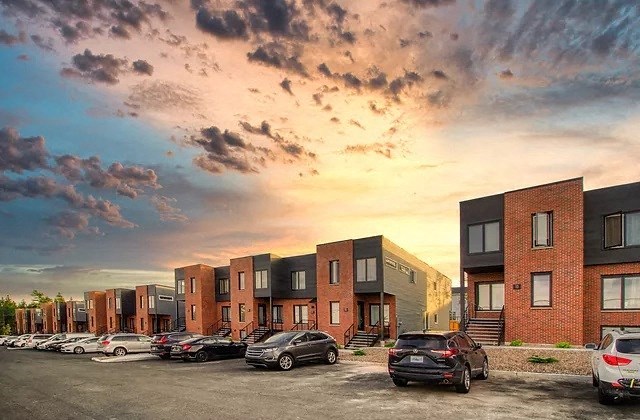a row of cars parked in a parking lot in front of buildings