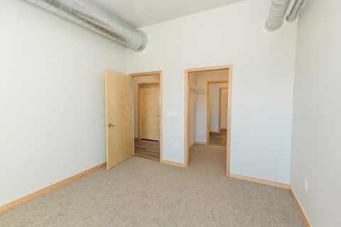 a room with white walls and a carpeted floor and two doors