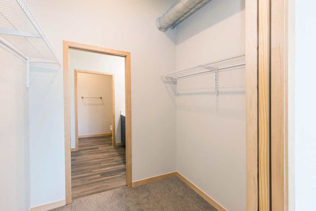 a walk in closet with a mirror and a door to a room with a hallway